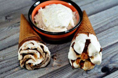 Çikolata ve karamel soslu dondurma külahları ve yanında vanilya kepçesi olan gevrek bir gofret külahında fındık, waffle bisküvisinde erimiş soğuk dondurma, yaz tatili konsepti.