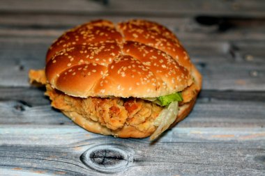 Kızarmış susamlı çörek, çıtır çıtır tavuklu sandviç, abur cubur konseptinin seçici odak noktası olan kızarmış tavuk filetosu ve marul ve mayonez ile kaplı baharatlı tavuk filetosu.