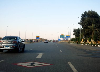 Kahire, Mısır, 3 Aralık 2022: Kahire Havalimanı yakınlarındaki Mısır otoyolu asfalt üzerinde bir yol uçağı tabelasıyla gürültü ve titreşim olasılığını gösteren alçaktan uçan uçaklar.