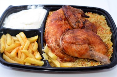 Arap mutfağından ızgara ızgara tavuk rengarenk Basmati pilavı ve patates kızartması sarımsak sosuyla servis edilen siyah bir tek kullanımlık tabakta servis ediliyor.