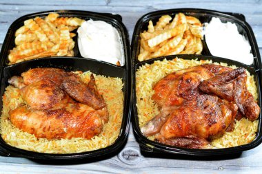 Arap mutfağından ızgara ızgara tavuk rengarenk Basmati pilavı ve patates kızartması sarımsak sosuyla servis edilen siyah bir tek kullanımlık tabakta servis ediliyor.