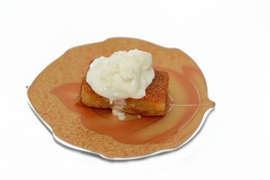 Üzerinde kremalı qeshta olan ve ballı şekerli şurup ile doymuş bir parça Basbosa, Basbusa genellikle Ramazan ayında pişirilen bir orta doğu tatlısıdır, Arap tatlı mutfağı arka planı