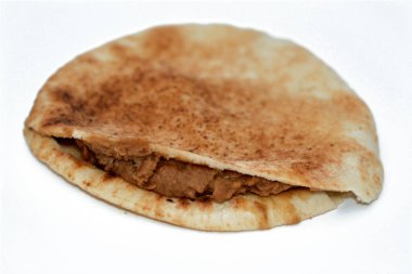 Yağlı, susamlı, kimyonlu, baharatlı ve beyaz arka planda izole edilmiş geleneksel popüler Mısır fasulyeli sandviçlerinin seçici odak noktası.