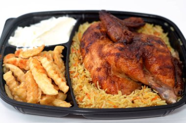 Arap mutfağından ızgara ızgara tavuk rengarenk Basmati pilavı ve patates kızartması sarımsak sosuyla servis edilen siyah bir tek kullanımlık tabakta servis ediliyor.