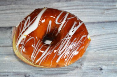 Üstünde karamel ve beyaz çikolata sosu olan halka bir çörek, jöleli, maya yetiştirilmiş, Amerikan usulü yüzük donutu, bol yağda kızartılmış hamur tatlısından yapılan yiyecek türü, seçici bir odaklanma.