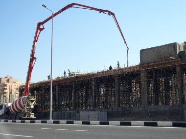 Kahire, Mısır, 30 Kasım 2022: Yolun kenarına kamyon monte edilmiş beton bir patlama pompası, yeni binanın inşaat alanındaki seçici beton kamyonun odak noktası olan yeni binaya beton dökülüyor