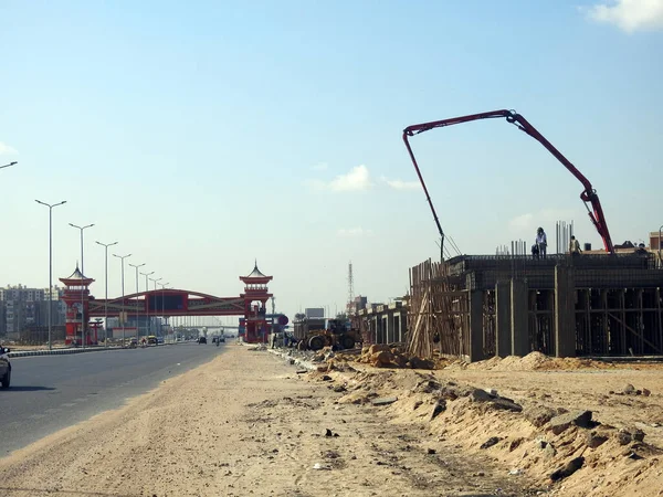 Kahire, Mısır, 7 Aralık 2022: Yolun kenarına kamyon monte edilmiş beton bir patlama pompası, yeni binanın inşaat alanındaki seçici odak noktası olan beton kamyona beton dökülüyor