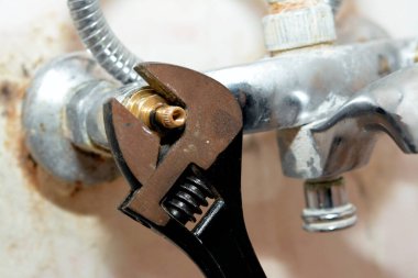 Musluk musluğu tamir eden bir musluk tamircisi kovanları değiştirmek için ayarlanabilir bir anahtarla gövdeyi döndürüyor, tesisat ve bakım konsepti evde, seçici bir odak noktası var.