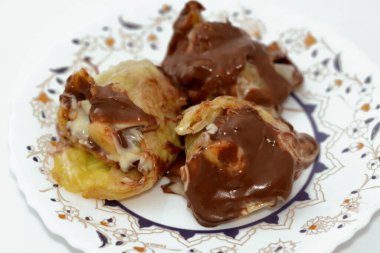 Muz, fındık, fındık, kuru üzüm, beyaz ve siyah çikolata karışımlı çikolata soslu tatlı çikolata ruloları.