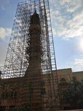 Eski Kahire kentindeki bir caminin eski bir İslami minaresinin inşası ve yenilenmesi için tahta iskeleler, bulutlu bir gökyüzüne karşı bir caminin yenilenmesi ve yeniden inşası, seçici bir odaklanma.