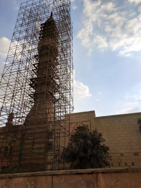 Eski Kahire kentindeki bir caminin eski bir İslami minaresinin inşası ve yenilenmesi için tahta iskeleler, bulutlu bir gökyüzüne karşı bir caminin yenilenmesi ve yeniden inşası, seçici bir odaklanma.