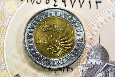 Mısır 1 LE EGP 'nin ters tarafı Mısır banknotu üzerinde bir Mısır Pound sikkesi, Mısır Polis Günü' nde uçan bir şahinle birlikte Mısır polis günü anısına Arap Çevirisi (Polis Günü 70 yıl)
