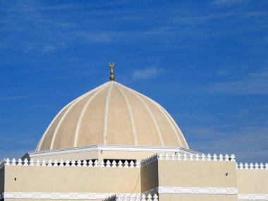 A big dome of a mosque against a lovely blue sky with clouds at the daylight, Mosques are the place for worship and prayers for Muslims where they perform 5 Islamic prayers daily, selective focus