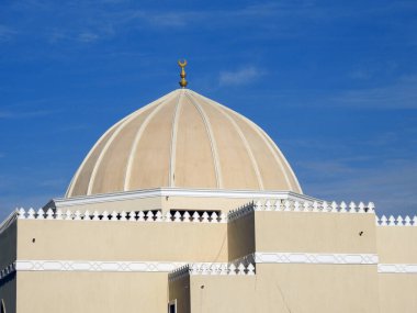 A big dome of a mosque against a lovely blue sky with clouds at the daylight, Mosques are the place for worship and prayers for Muslims where they perform 5 Islamic prayers daily, selective focus