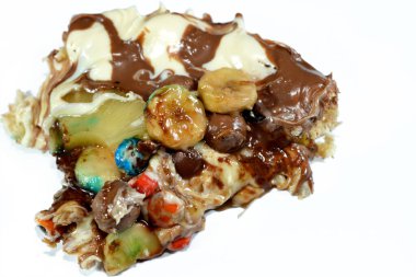 Chocolate mixture with biscuit and different types of chocolate pieces and cream with fresh pineapple ananas and bananas pieces on top on a dough baked and ready to be served, selective focus