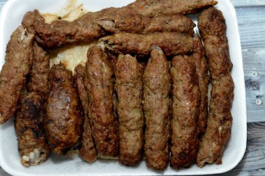Arabic cuisine traditional food beef Kofta, kebab and tarb kofta shish which is minced meat wrapped in lamb fat charcoal grilled and served on flatbread, oriental grilled barbecued meat food