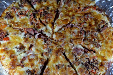 Italian pizza with pieces of pastrami, meat, beef and salami, with mozzarella cheese and peppers, baked pizza with ketchup ready to be served as a lunch and snack, fast unhealthy food concept