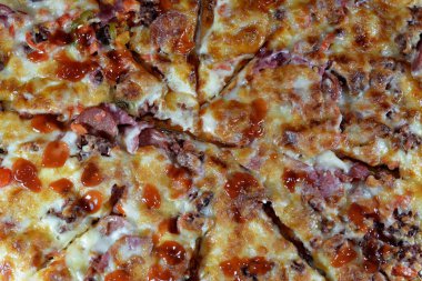 Italian pizza with pieces of pastrami, meat, beef and salami, with mozzarella cheese and peppers, baked pizza with ketchup ready to be served as a lunch and snack, fast unhealthy food concept