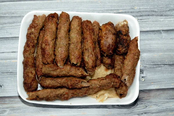 Arabic cuisine traditional food beef Kofta, kebab and tarb kofta shish which is minced meat wrapped in lamb fat charcoal grilled and served on flatbread, oriental grilled barbecued meat food