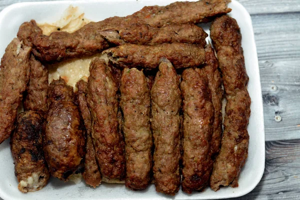 Arabic cuisine traditional food beef Kofta, kebab and tarb kofta shish which is minced meat wrapped in lamb fat charcoal grilled and served on flatbread, oriental grilled barbecued meat food