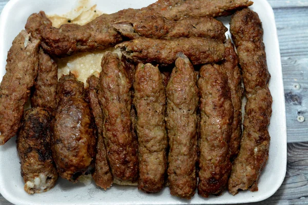 Arabic cuisine traditional food beef Kofta, kebab and tarb kofta shish which is minced meat wrapped in lamb fat charcoal grilled and served on flatbread, oriental grilled barbecued meat food