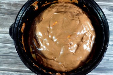 A pie baked dough covered with chocolate and stuffed with pieces of chocolate, biscuit, banana, cake, caramel and brownies, ready to be served, selective focus of a chocolate sweet pastry