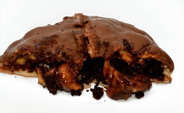 A pie baked dough covered with chocolate and stuffed with pieces of chocolate, biscuit, banana, cake, caramel and brownies, ready to be served, selective focus of a chocolate sweet pastry