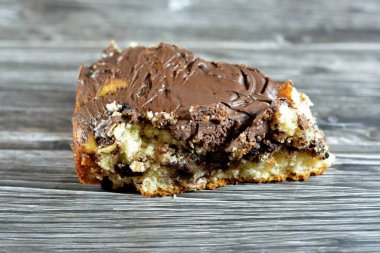 baked dough covered with chocolate and stuffed with pieces of chocolate, biscuit, cake, caramel and brownies, ready to be served, selective focus of a chocolate sweet pastry cake