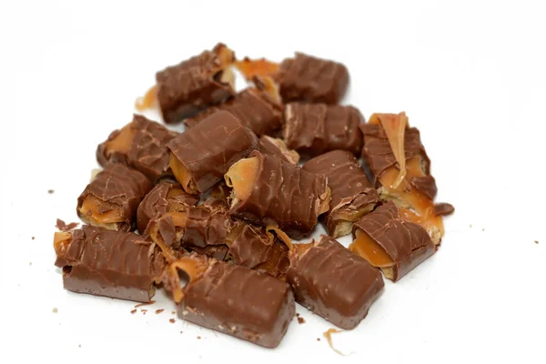small pieces of chocolate bars sticks filled with biscuits, caramel and chocolate isolated on white background, selective focus of confectionery sweet sugary dessert meal, weight gain concept