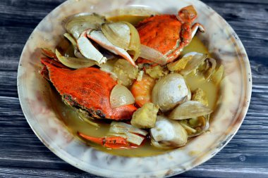 Hot soup meal of various fresh seafood marine crabs, shrimps, clams, mussels, gandofli, oysters, crab sticks, calamari, squid and fish fillet cooked on hot steam merged in water, milk, lime and spices