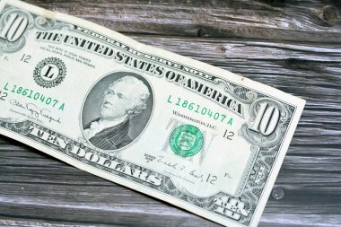 obverse side of old 10 $ ten American dollars bill banknote series 1988 features the portrait of Alexander Hamilton, who served as the first U.S. Secretary of the Treasury isolated on wood background