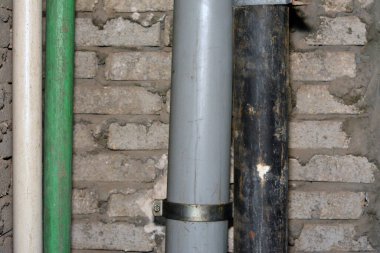 Sewer and water pipes fixed on a bricks with cement wall, plumbing fixing concept of water supply and sewer services, selective focus of the services area of a building with plumbing tubes