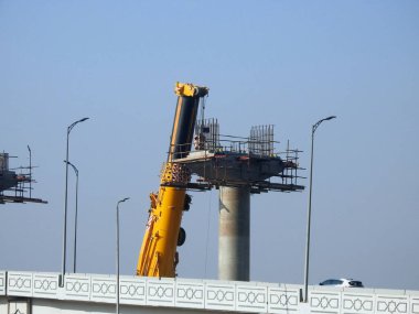 Cairo, Egypt, February 15 2023: Construction site of new Cairo monorail overhead transportation system that is still under construction with a heavy mobile crane fixing and fitting objects