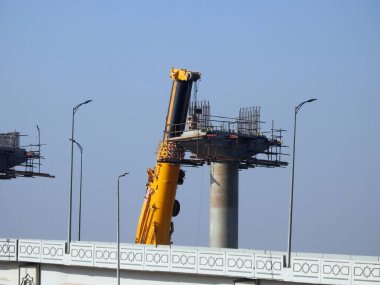Cairo, Egypt, February 15 2023: Construction site of new Cairo monorail overhead transportation system that is still under construction with a heavy mobile crane fixing and fitting objects