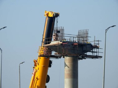 Cairo, Egypt, February 15 2023: Construction site of new Cairo monorail overhead transportation system that is still under construction with a heavy mobile crane fixing and fitting objects