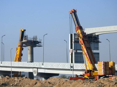 Cairo, Egypt, February 15 2023: Construction site of new Cairo monorail overhead transportation system that is still under construction with a heavy mobile crane fixing and fitting objects