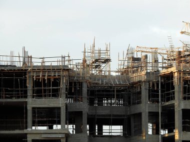A construction site of new residential buildings and high rise with cranes to transport heaving objects, selective focus of an under construction buildings with cranes at daylight time