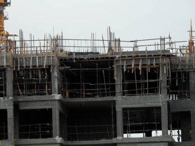 A construction site of new residential buildings and high rise with cranes to transport heaving objects, selective focus of an under construction buildings with cranes at daylight time
