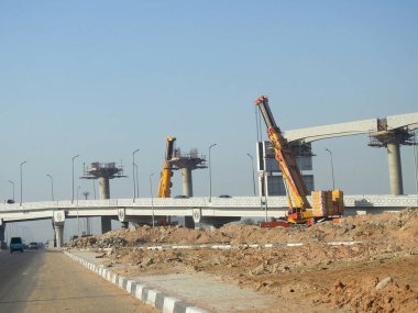 Cairo, Egypt, February 15 2023: Construction site of new Cairo monorail overhead transportation system that is still under construction with a heavy mobile crane fixing and fitting objects