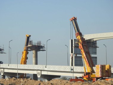 Cairo, Egypt, February 15 2023: Construction site of new Cairo monorail overhead transportation system that is still under construction with a heavy mobile crane fixing and fitting objects