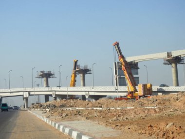 Cairo, Egypt, February 15 2023: Construction site of new Cairo monorail overhead transportation system that is still under construction with a heavy mobile crane fixing and fitting objects