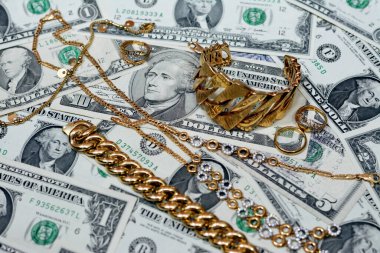 Jewellery or jewelry with USD American dollars cash money banknotes, brooches, rings, necklaces, earrings, pendants, bracelets, chain and cufflinks, Gold price in US dollar concept, selective focus