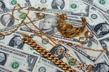Jewellery or jewelry with USD American dollars cash money banknotes, brooches, rings, necklaces, earrings, pendants, bracelets, chain and cufflinks, Gold price in US dollar concept, selective focus