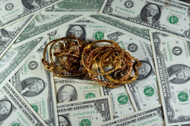 Jewellery or jewelry with USD American dollars cash money banknotes, brooches, rings, necklaces, earrings, pendants, bracelets, chain and cufflinks, Gold price in US dollar concept, selective focus