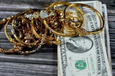Jewellery or jewelry with USD American dollars cash money banknotes, brooches, rings, necklaces, earrings, pendants, bracelets, chain and cufflinks, Gold price in US dollar concept, selective focus