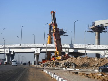 Cairo, Egypt, February 16 2023: Construction site of new Cairo monorail overhead transportation system that is still under construction with a heavy mobile crane fixing and fitting objects