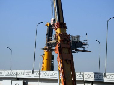 Cairo, Egypt, February 16 2023: Construction site of new Cairo monorail overhead transportation system that is still under construction with a heavy mobile crane fixing and fitting objects