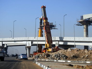 Cairo, Egypt, February 16 2023: Construction site of new Cairo monorail overhead transportation system that is still under construction with a heavy mobile crane fixing and fitting objects
