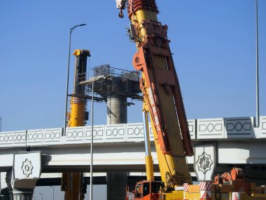 Cairo, Egypt, February 16 2023: Construction site of new Cairo monorail overhead transportation system that is still under construction with a heavy mobile crane fixing and fitting objects