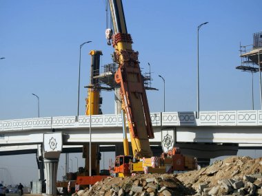 Cairo, Egypt, February 16 2023: Construction site of new Cairo monorail overhead transportation system that is still under construction with a heavy mobile crane fixing and fitting objects